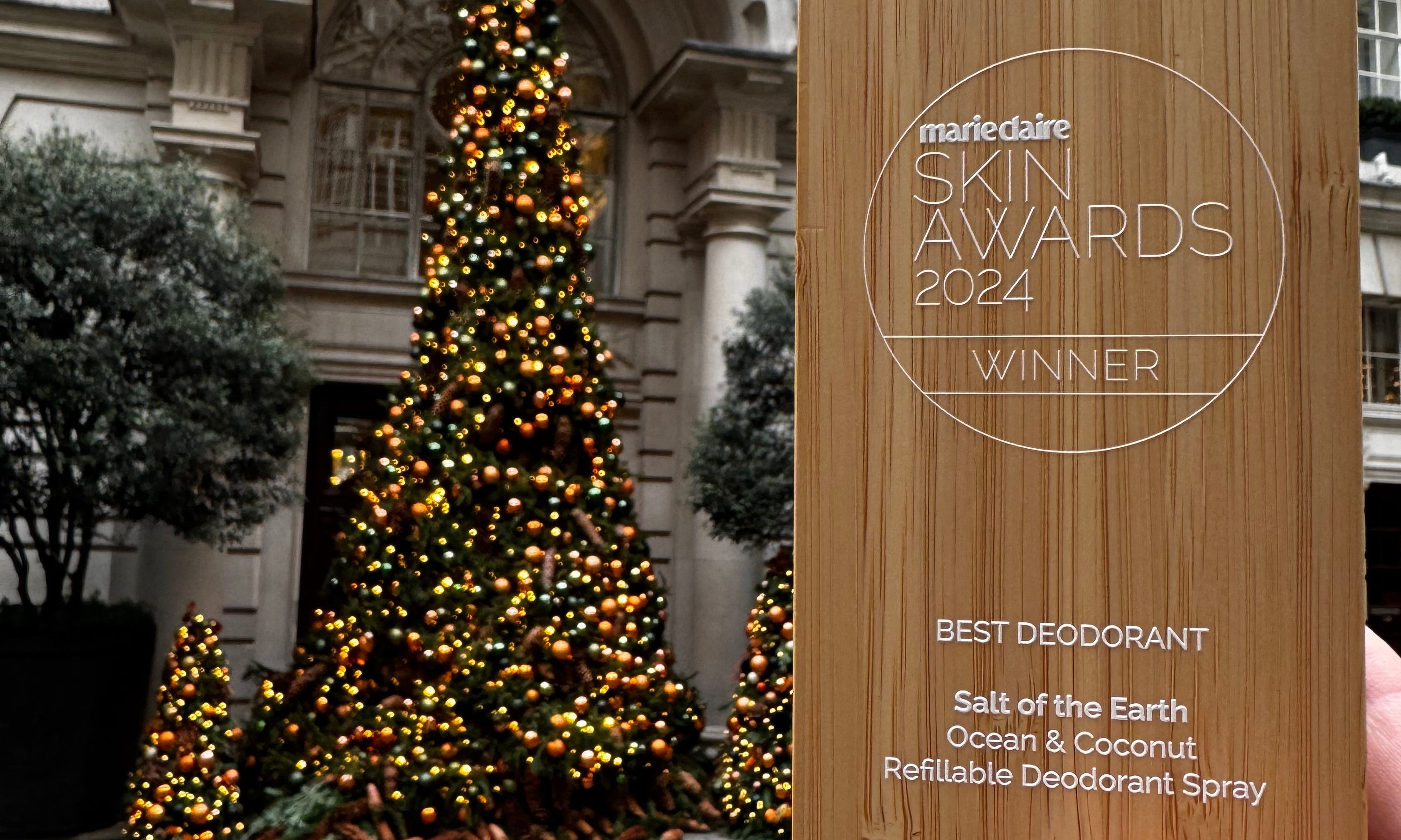 Marie Claire Beauty Award 2024 held against a decorated Christmas tree, celebrating Ocean & Coconut Spray Deodorant's win