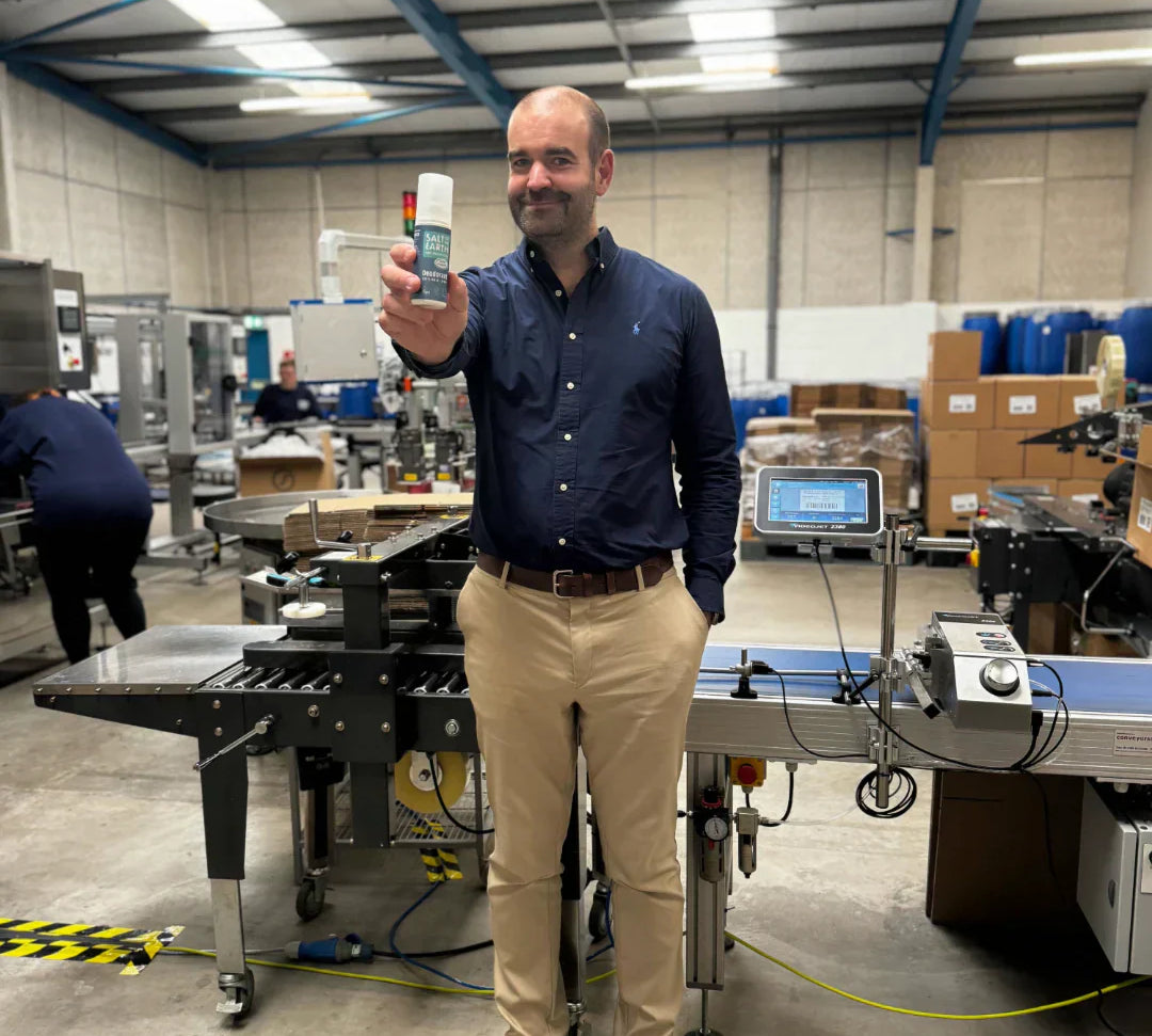 Thomas Laird, MD of Salt of the Earth, holding Ocean & Coconut natural deodorant spray at the end of production line